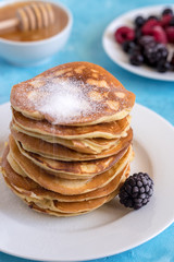 Fluffy and delicate pancakes with powdered sugar and berries.