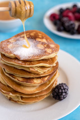 Fluffy and delicate pancakes with honey, powdered sugar and berries.