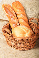 A wicker basket full of freshly baked hot rolls with sesame seeds and linseed