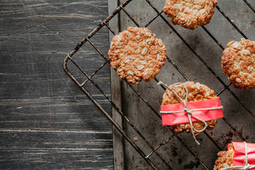 Anzac cookies on a cooling rack with red paper on the vintage black wood
