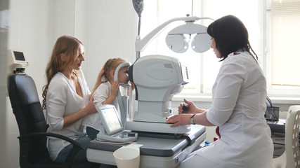 Doctor optometrist in clinic checking little girl's vision - children's ophthalmology - obrazy, fototapety, plakaty