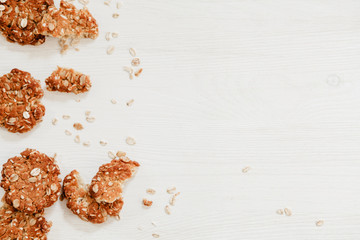Homemade oatmeal cookies on a white wood with oats