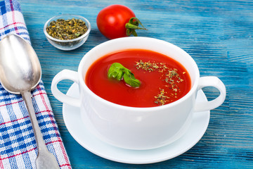 Cream soup of fresh red tomatoes on blue wooden background