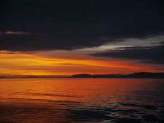 Beautiful orange sunset in Alaska waters - amazing contrast with sunset and clounds