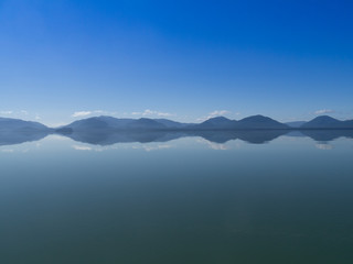 Alaska sea so calm that looks like a mirror, with montains and clounds