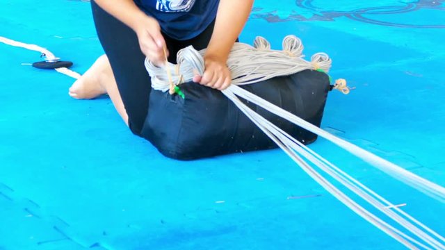 Parachute activity, extreme sport danger. Young instructor preparing,controlling and fixing skydiving equipment before the flight for person's safety. Main parachute, long white cords