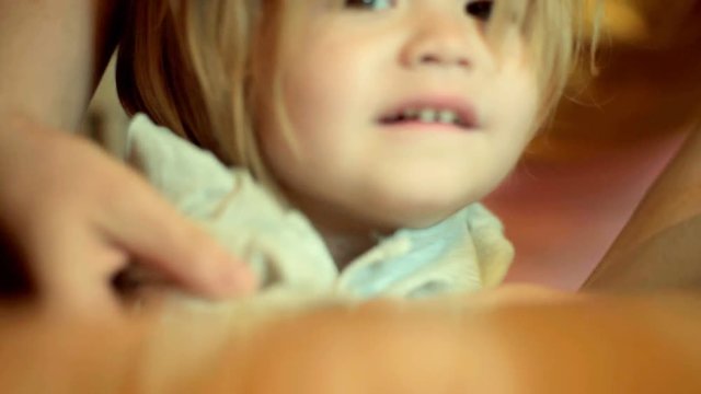 Mom dresses a beautiful baby closeup. Boy with long hair yawns gape in the morning. Cite child wakes up and dresses in kindergarten or at home. Tired sleepy kid. Beautiful baby face. Morning toddler 