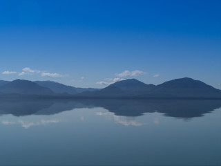 Alaska sea so calm that looks like a mirror, with montains and clounds