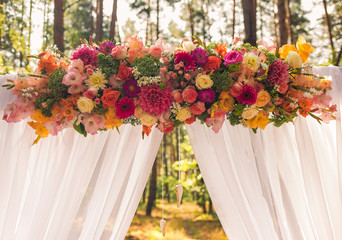 Closeup view of beautiful colorful floral elements of wedding decorations. Settings for romantic wedding ceremony outside at sunny forest. Horizontal color photography. 