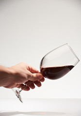 One hand hold red wine glass