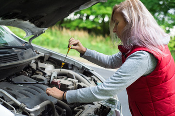 Obraz na płótnie Canvas Girl checks the oil in the car's engine