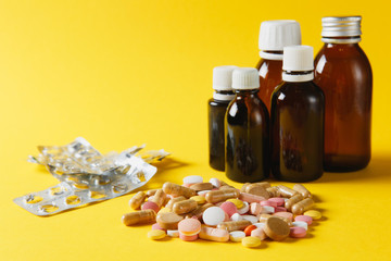 Medication white colorful round tablets arranged abstract on yellow color background. Bottle vial...