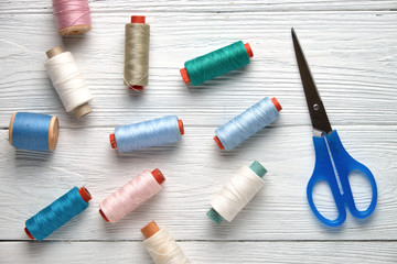 Sewing accessories, threads, scissors. Accessories for needlework on a white wooden background. Top view.