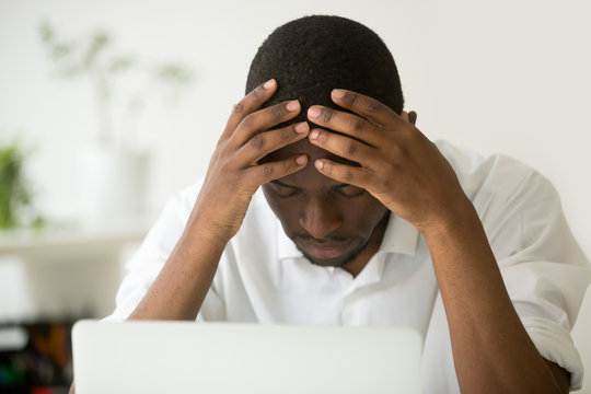 Frustrated African Businessman Feeling Exhausted Depressed Holding Head In Hands Sitting In Front Of Laptop, Hopeless Stressed Black Man Lost All Money Online, Sad Upset Employee Tired Or Overwork