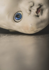 Half face portrait of old doll with one blue eye.