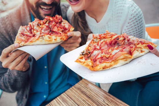 Fototapeta Couple eating pizza outdoors in a outdoor cafe, close up.