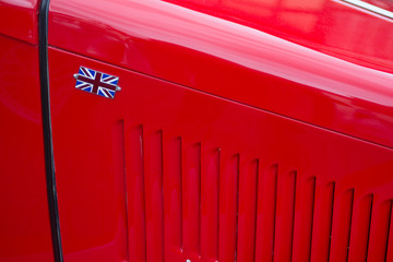 bright red engine hood on vintage car with British flag