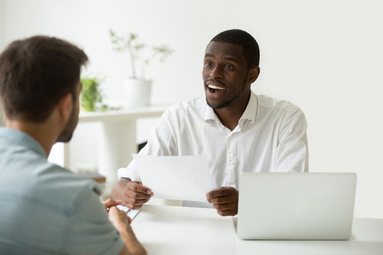 Good first impression at job interview concept, excited african hr manager impressed by career achievements in resume of caucasian candidate, black employer amazed by accomplishments in applicants cv