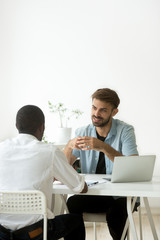 Two diverse young businessmen talking discussing new project idea, caucasian hr holding job interview with african candidate, multiracial colleagues working together in office teamwork, vertical view