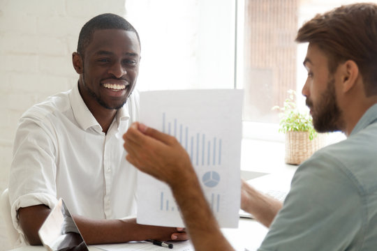 Caucasian advisor consulting african american client about loan, mortgage or insurance showing financial statistics, white adviser talking to black smiling businessman about new project investment