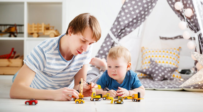happy family father and son playing in toy car in playroom