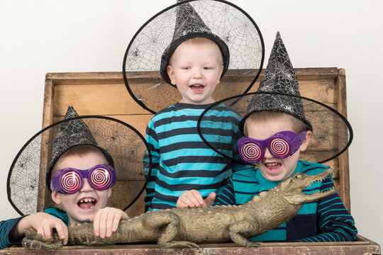 Happy children in elegant green clothes play at home with a stuffed crocodile. Boys in carnival glasses and a hat are posing for a fashion magazine