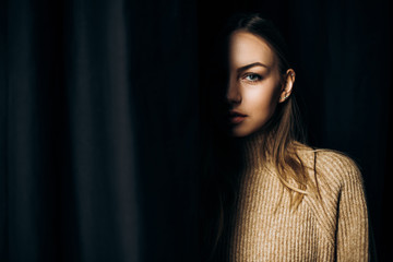Portrait near a black curtain of an attractive blue-eyed woman that only shows half of her face