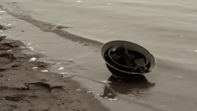 Footage of world war era brodie soldier helmet on beach.