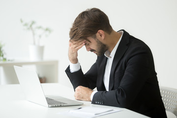 Depressed unsuccessful businessman feels terrible headache, distraught stressed entrepreneur...