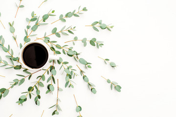 Cup of coffee in frame of eucalyptus branch. Flat lay, top view.