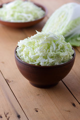 Peking cabbage in earthenware, sliced cabbage on a wooden background, half cabbage for cooking, homemade cuisine, vegetarian food, retro style