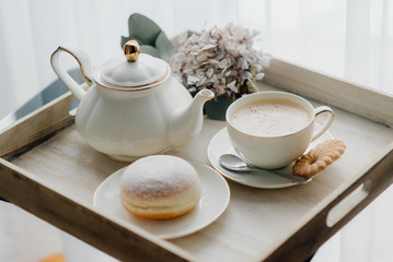 Donuts on plate on woode board with hot coffee for breakfast