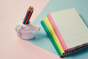 stationery items pop art pastel background unicorn pencil holder and note-books © allasimacheva