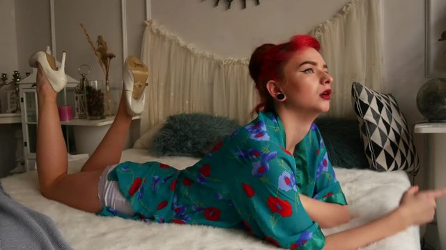 Beautiful red-haired girl on the bed. A woman in a pinup style at a photo shoot.