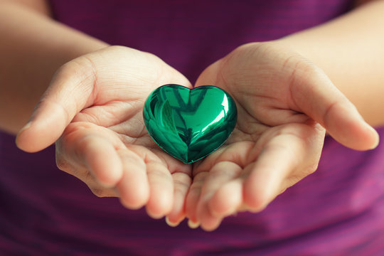 Green heart shape in woman hand
