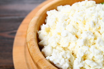 Home cottage cheese in a bowl on a wooden table.