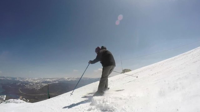 Slow motion as a man skis in slushy snow at a mountain ski resort