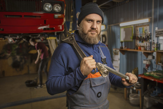 A bearded car mechanic works in the garage