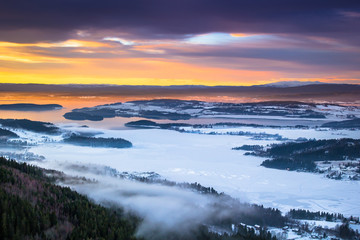 Obraz premium Grat view of hills and fjords cover in snow during sunset