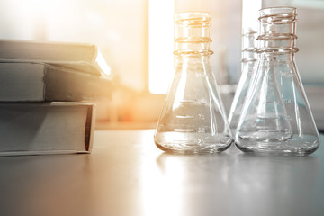 three flask in science laboratory with book for education or study with soft window light background