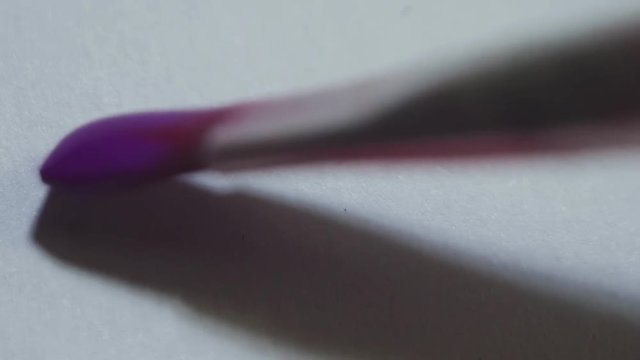 Paintbrush drawing purple watercolor line on white paper canvas, macro close up