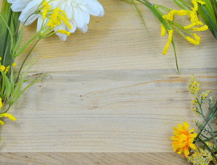 Obraz premium Spring border of artificial yellow flowers on rustic wooden background. Copy space for your message.