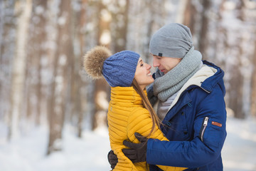 Portrait of young couple looking face to face in a forest in the winter