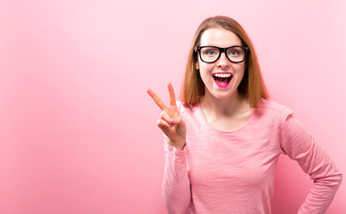 Young woman giving the peace sign on a solid background