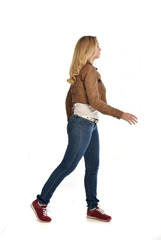 full length portrait of girl wearing brown leather jacket and jeans.   standing pose facing away...