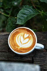 cup of latte art coffee on wooden background