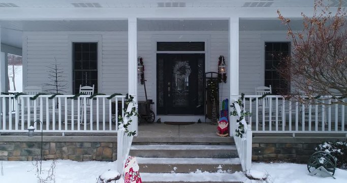 A personal perspective slowly approaching the front door of a house and porch decorated for Christmas.  	