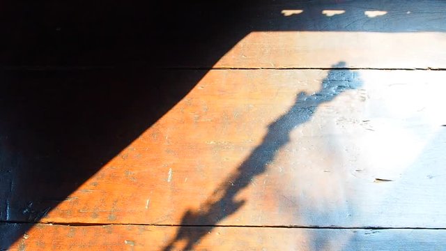 Old red brown wooden stripe tile floor, bright sunlight shining diagonal shade and Thai traditional culture Buddhist triangle flower hanging shadow from window outside, moving, turning, from wind blow