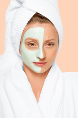 Beauty Treatments. Woman applying facial mask at spa