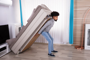 Fototapeta premium Young Man Lifting Sofa